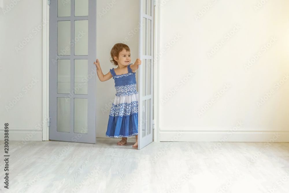 Little cute sweet smiling girl in blue dress dancing in bright light living room at home and laughing. Childhood, preschool, youth, relax concept Little cute sweet smiling girl in blue dress dancing in bright light living room at home and laughing. Childhood, preschool, youth, relax concept