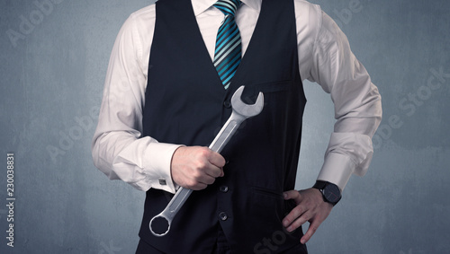 Young, handsome, cute businessman holding tool with grey background photo