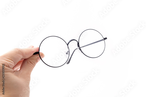 Round black-rimmed glasses are located frontally, Hand holds glasses. Isolated on a light background. 