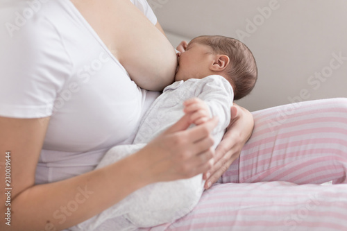 Young mother breastfeeding her newborn baby son. Happy mom hugging her babyboy close-up. Breast feeding and lactation infant concept. photo