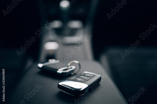 Car ignition keys resting on the armrest of a modern vehicle interior, representing automotive rental services or private ownership in a premium setting.