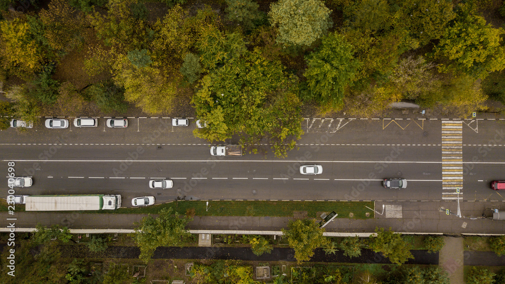 Aerial Drone Flight top down view of freeway busy city rush hour heavy traffic jam highway.  Aerial view of the vehicular intersection,  traffic at peak hour with cars on the road, fly under trees.