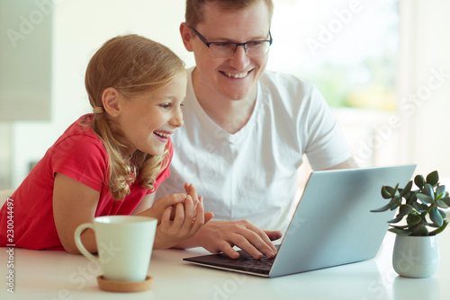 Happy young father have fun with his pretty daughter during working with laptop at home © spass