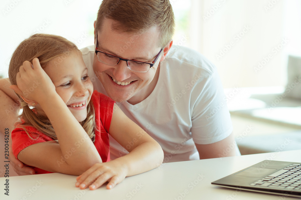 Happy young father have fun with his pretty daughter during working with laptop at home Happy young father have fun with his pretty daughter during working with laptop at home