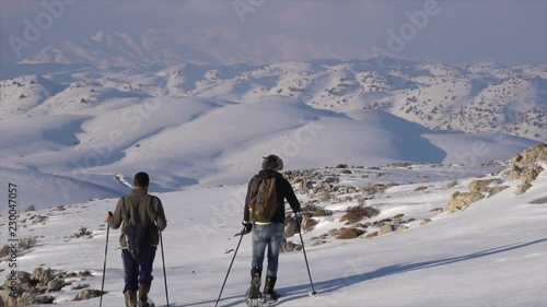 Two men snowshowing in a vast expanse of cascaded snow mountains 2 photo