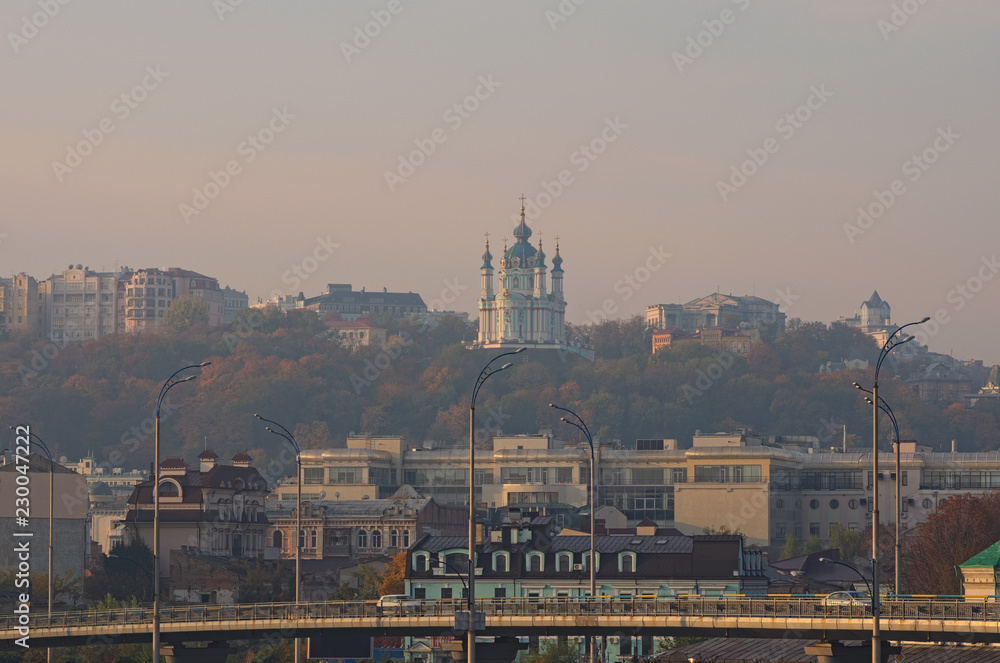 Picturesque view of St. Andrew's Church at the hill and one of the oldest district in Kyiv ? Podil during autumn sunrise. Landscape of Kyiv (Kiev), Ukraine