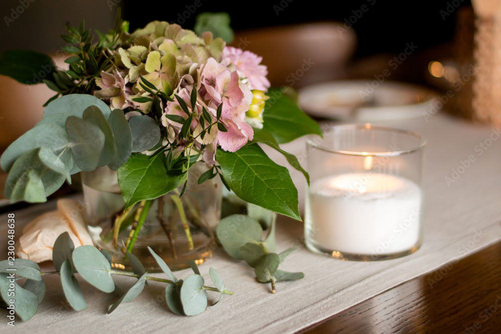 a bouquet of flowers and a candle on the table