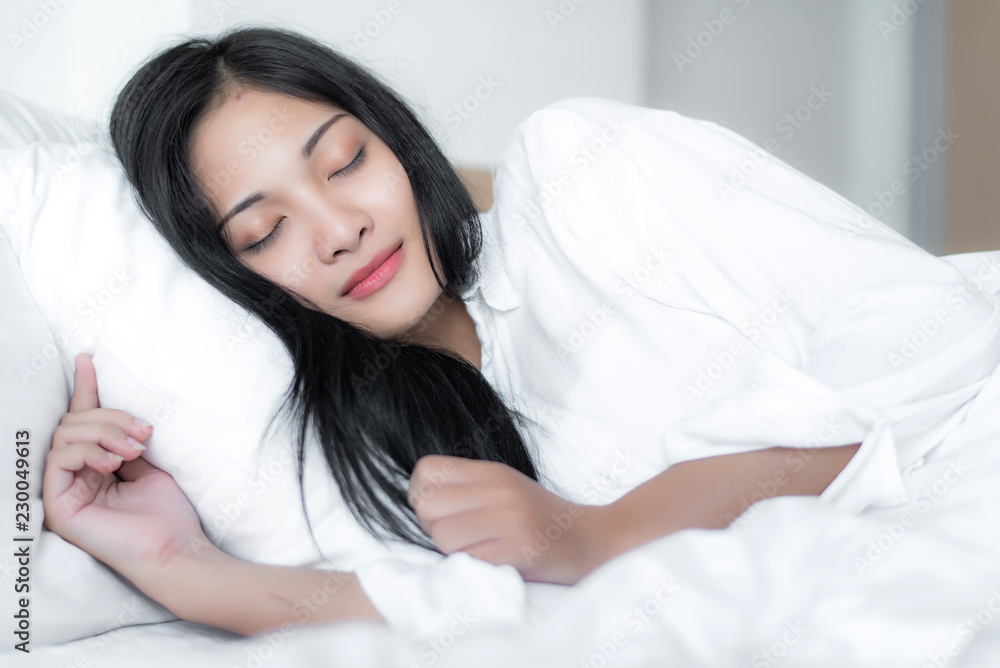 Beautiful young pretty Asian woman wake up and make happy smile with white shirt at the white bed in the morning. Beautiful young pretty Asian woman wake up and make happy smile with white shirt at the white bed in the morning.