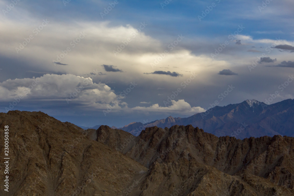 desert mountains against the backdrop of snowy mountains under heavy sky