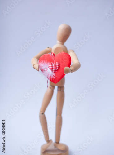 Wood Figure Mannequin holding a red heart on white background