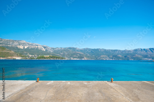 Banks of the Adriatic sea bay, with a rusted anchor to tie the boat, at the moment empty. Waves of a blue sea, mountains and villages in the background. Blue spring sky. Silo, island Krk, Croatia. © savantermedia