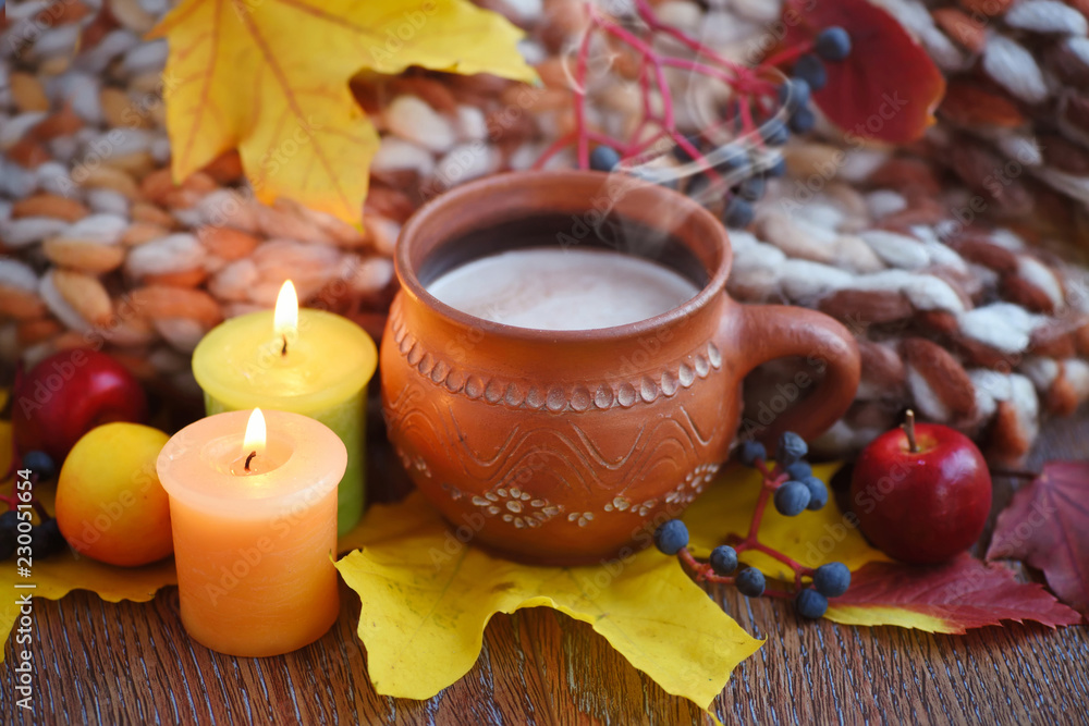 Cozy autumn composition with a cup of hot coffee, candles, fall leaves and scarf on a wooden background Cozy autumn composition with a cup of hot coffee, candles, fall leaves and scarf on a wooden background