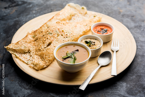 Onion rava masala dosa is a South Indian instant breakfast served with chutney and sambar over moody background. selective focus photo