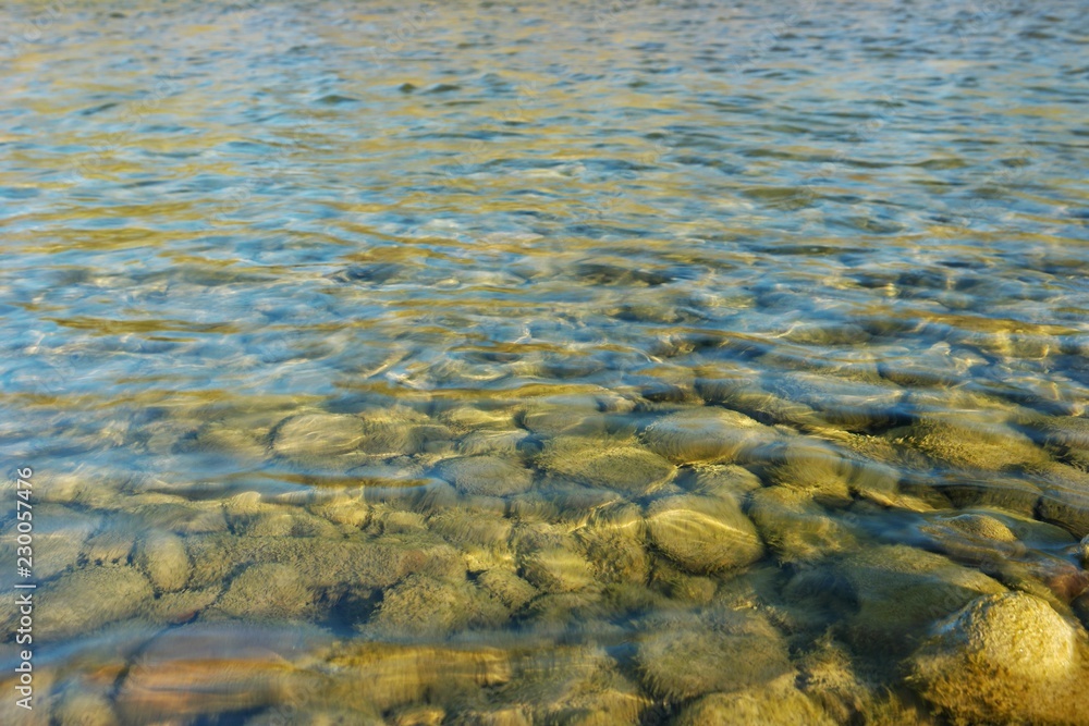 Pebbles under water in the rays of the sun, a mountain river, background Pebbles under water in the rays of the sun, a mountain river, background