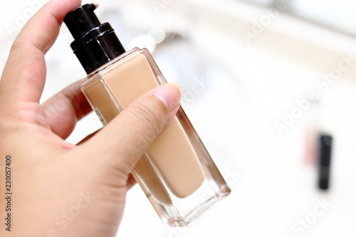 化粧をするためにファンデーションのボトルを持つ女性
