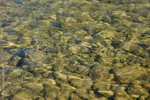 Pebbles under water in the rays of the sun, a mountain river, background