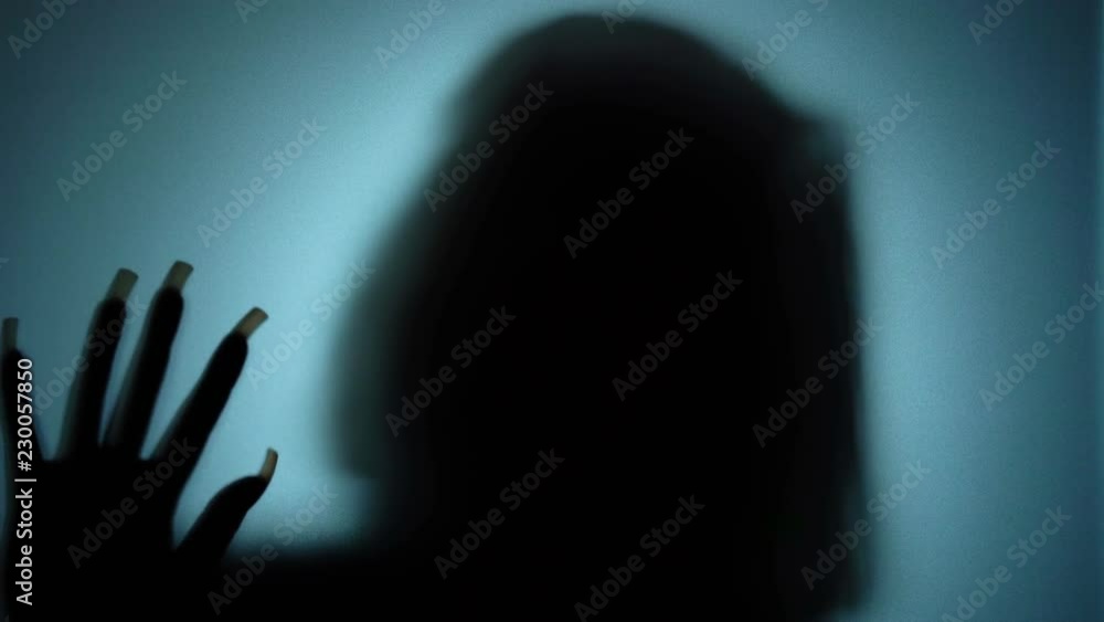 Deranged woman with long crooked nails beating on glass, evil witch, ghost. Blood-chilling horror thriller shot Deranged woman with long crooked nails beating on glass, evil witch, ghost. Blood-chilling horror thriller shot