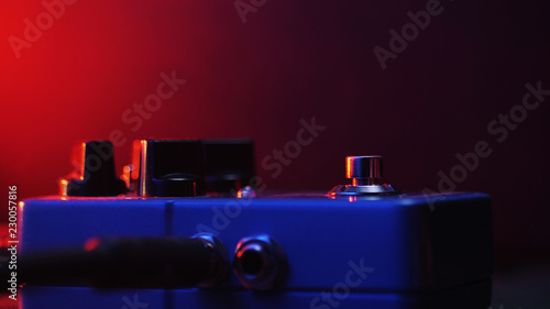 Extremely close up of button for effect electro guitar pedal. Red neon light in night club during show concert.