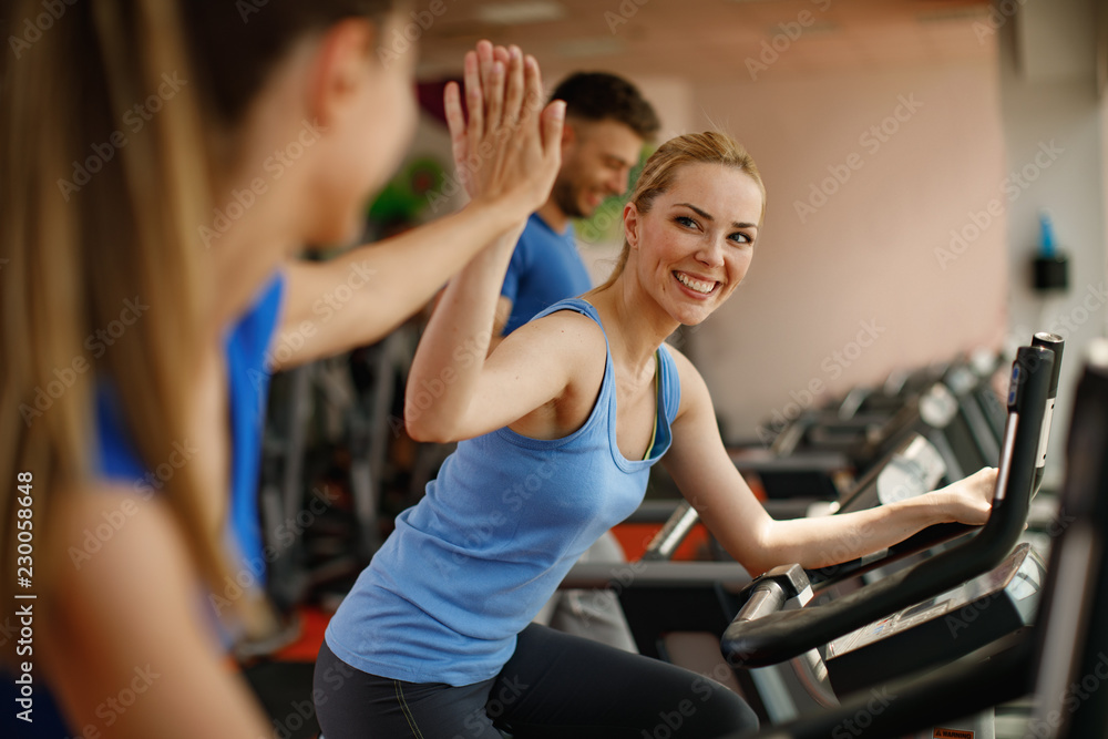 Young woman and man warming up on bikes in the gym Young woman and man warming up on bikes in the gym