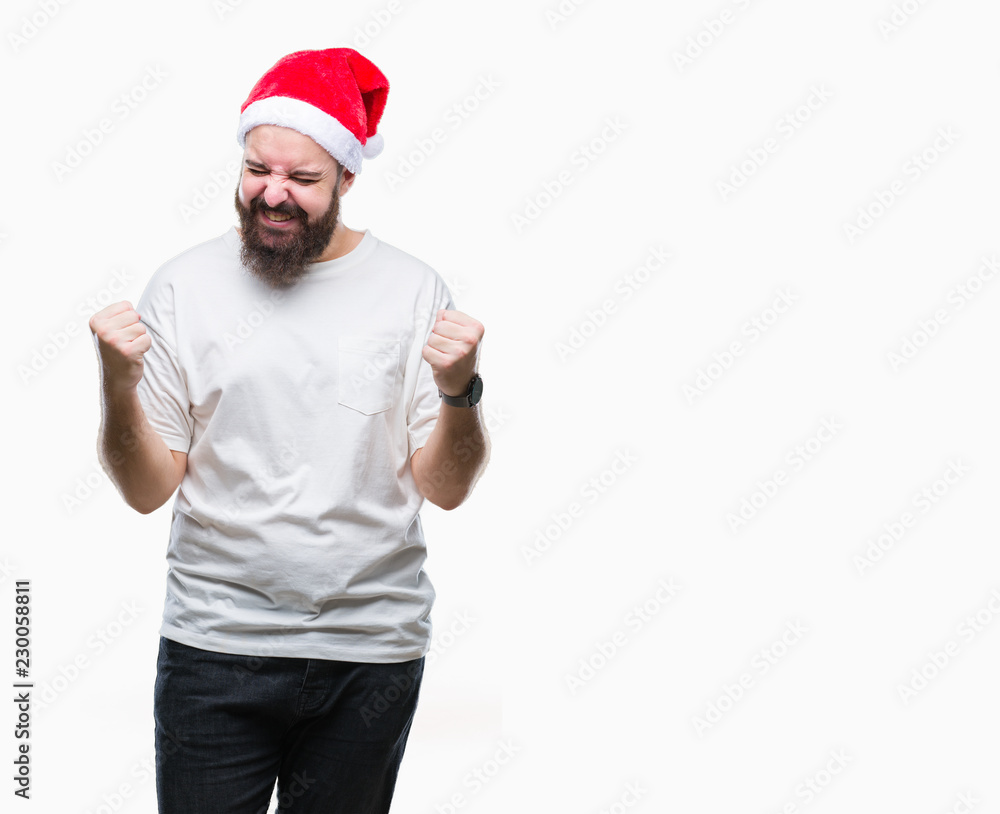Young caucasian hipster man wearing christmas hat over isolated background very happy and excited doing winner gesture with arms raised, smiling and screaming for success. Celebration concept. Young caucasian hipster man wearing christmas hat over isolated background very happy and excited doing winner gesture with arms raised, smiling and screaming for success. Celebration concept.