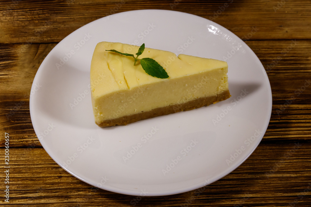 Piece of tasty sweet New York cheesecake in a white plate on wooden table
