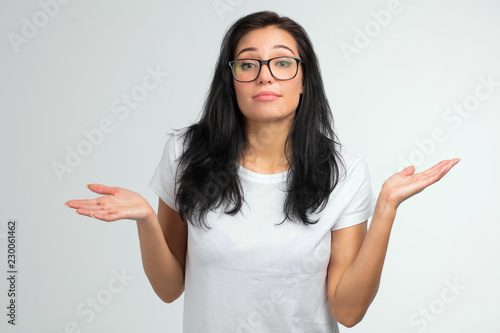 Quadro em tela close up portrait of a pretty woman in glasses shrugging shoulders isolated on a white background