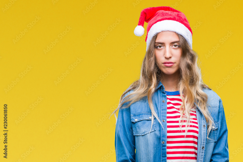 Beautiful young blonde woman wearing christmas hat over isolated background with serious expression on face. Simple and natural looking at the camera. Beautiful young blonde woman wearing christmas hat over isolated background with serious expression on face. Simple and natural looking at the camera.