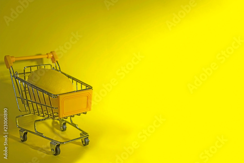Shopping cart in front of yellow background, close up, isolated
