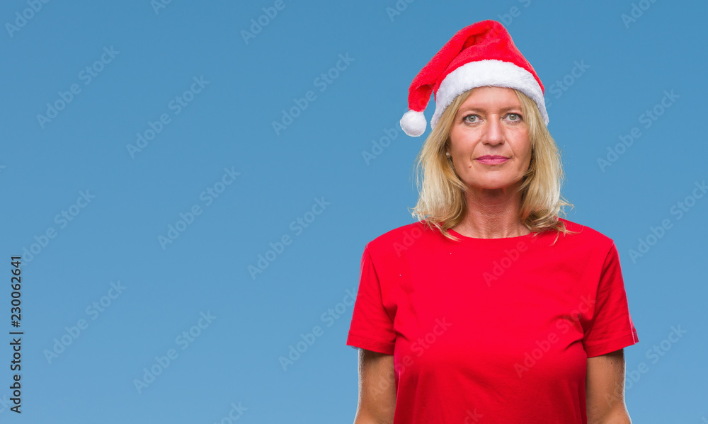Middle age blonde woman wearing christmas hat over isolated background with serious expression on face. Simple and natural looking at the camera. Middle age blonde woman wearing christmas hat over isolated background with serious expression on face. Simple and natural looking at the camera.