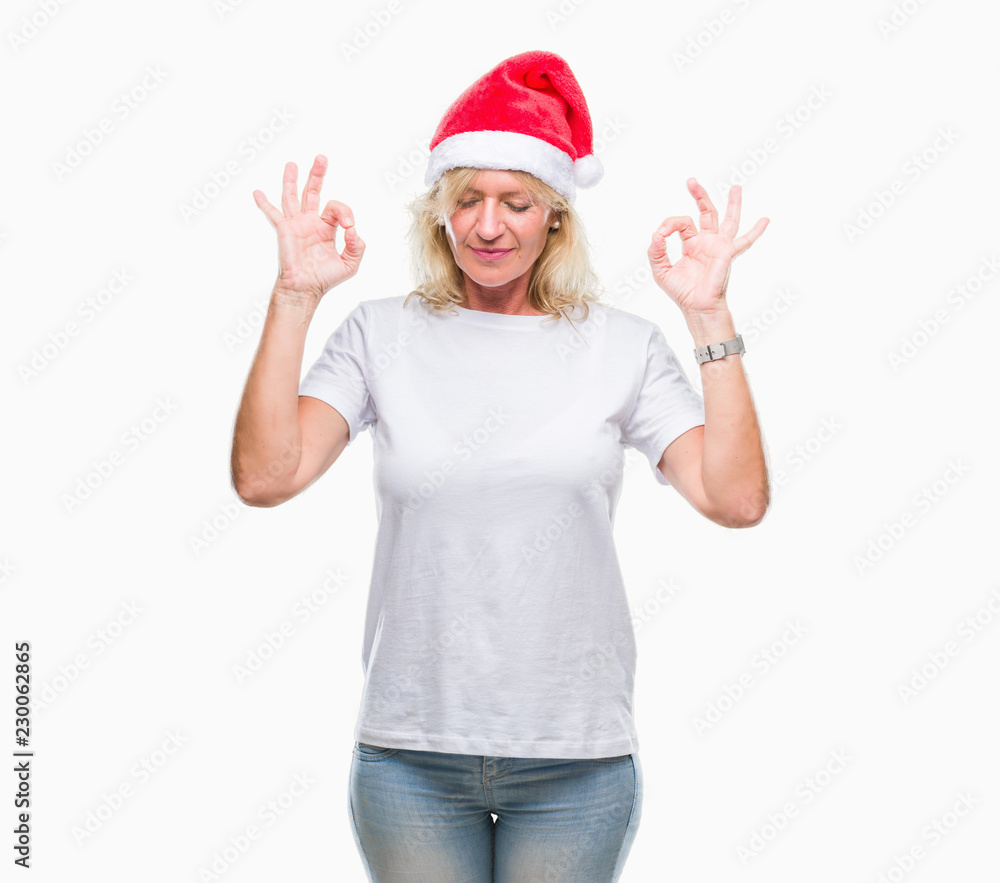 Middle age blonde woman wearing christmas hat over isolated background relax and smiling with eyes closed doing meditation gesture with fingers. Yoga concept. Middle age blonde woman wearing christmas hat over isolated background relax and smiling with eyes closed doing meditation gesture with fingers. Yoga concept.