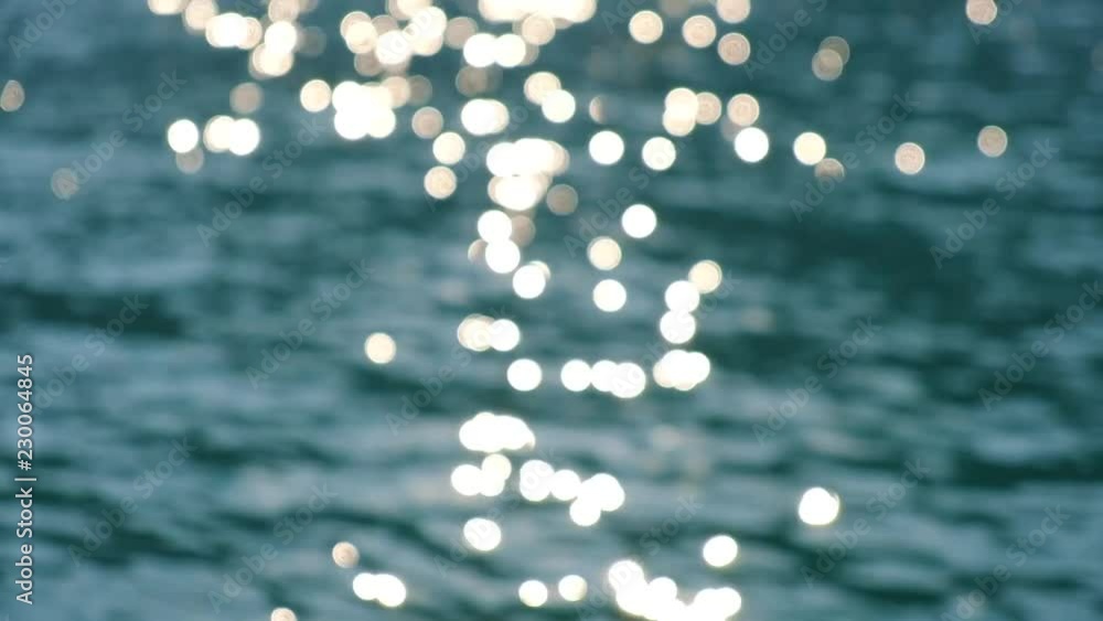 Sparkling bright wavy water shining at sunny summer day in slow motion. Abstract blurry background of seaside