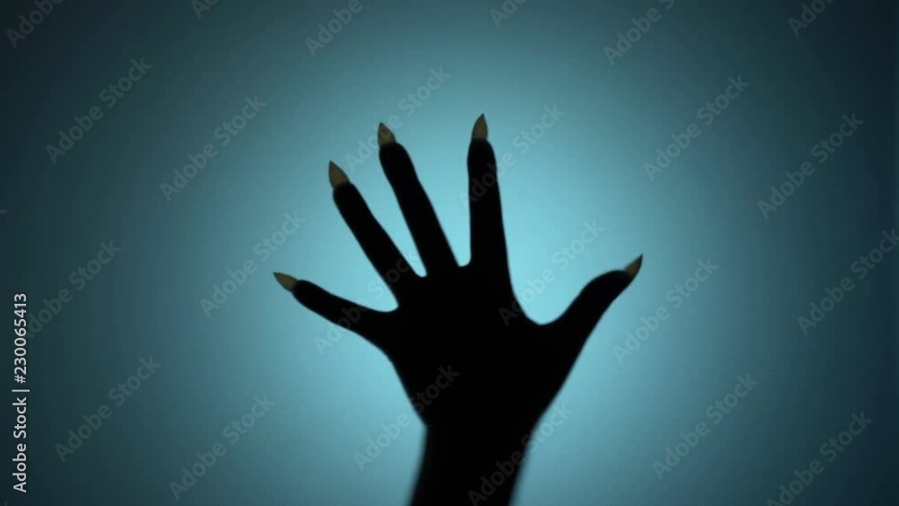 Creepy hand with long sharp nails beating on glass, blood-chilling horror scene. Blood-chilling horror thriller shot Creepy hand with long sharp nails beating on glass, blood-chilling horror scene. Blood-chilling horror thriller shot
