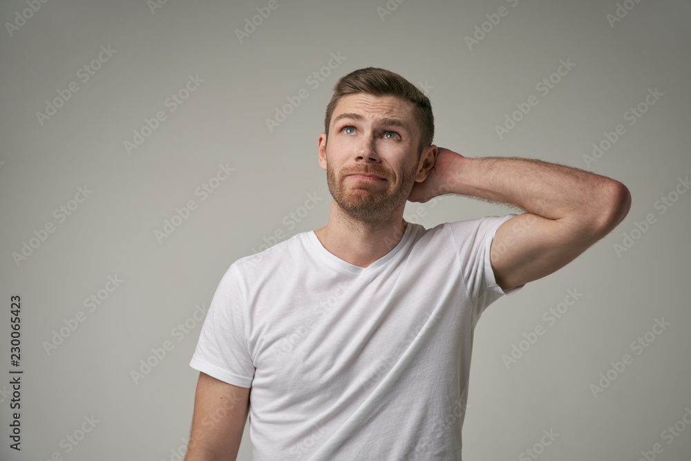 Attractive trendy young male freelancer with beard looking away with confused expression, scratching head, on isolated grey background. Handsome guy student remembers information for exam Attractive trendy young male freelancer with beard looking away with confused expression, scratching head, on isolated grey background. Handsome guy student remembers information for exam