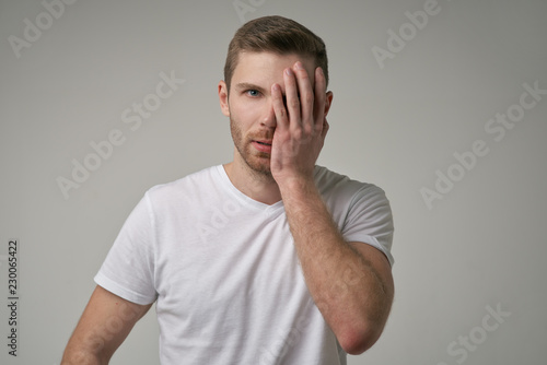 Beautiful bearded man covering face with his hand, a sign Facepalm, fatigue after a big party, relaxing that he wants to sleep isolated on white background. Unshaven attractive man in the Studio