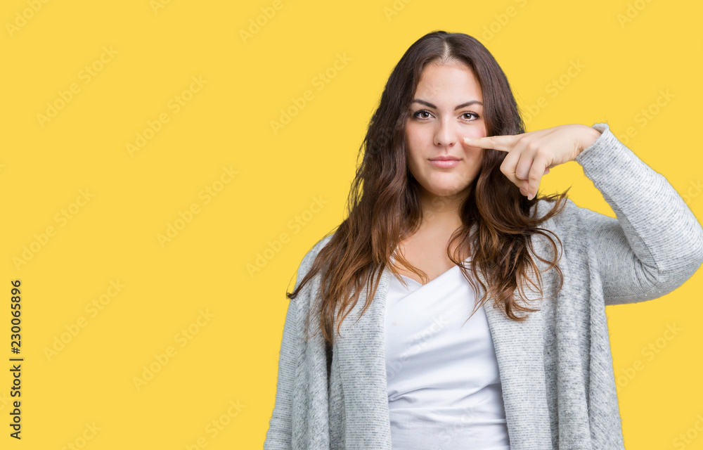 Beautiful plus size young woman wearing winter jacket over isolated background Pointing with hand finger to face and nose, smiling cheerful Beautiful plus size young woman wearing winter jacket over isolated background Pointing with hand finger to face and nose, smiling cheerful
