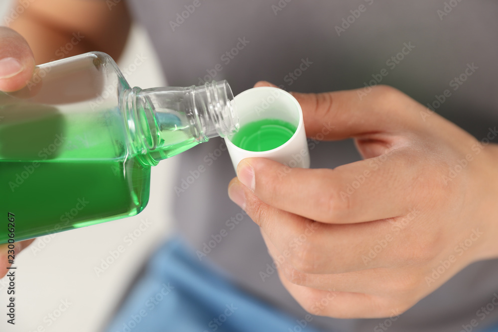 Man pouring mouthwash from bottle into cap, closeup. Teeth care Man pouring mouthwash from bottle into cap, closeup. Teeth care