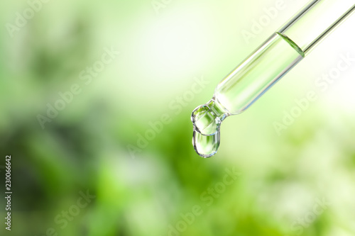 Pipette with essential oil on blurred background. Space for text