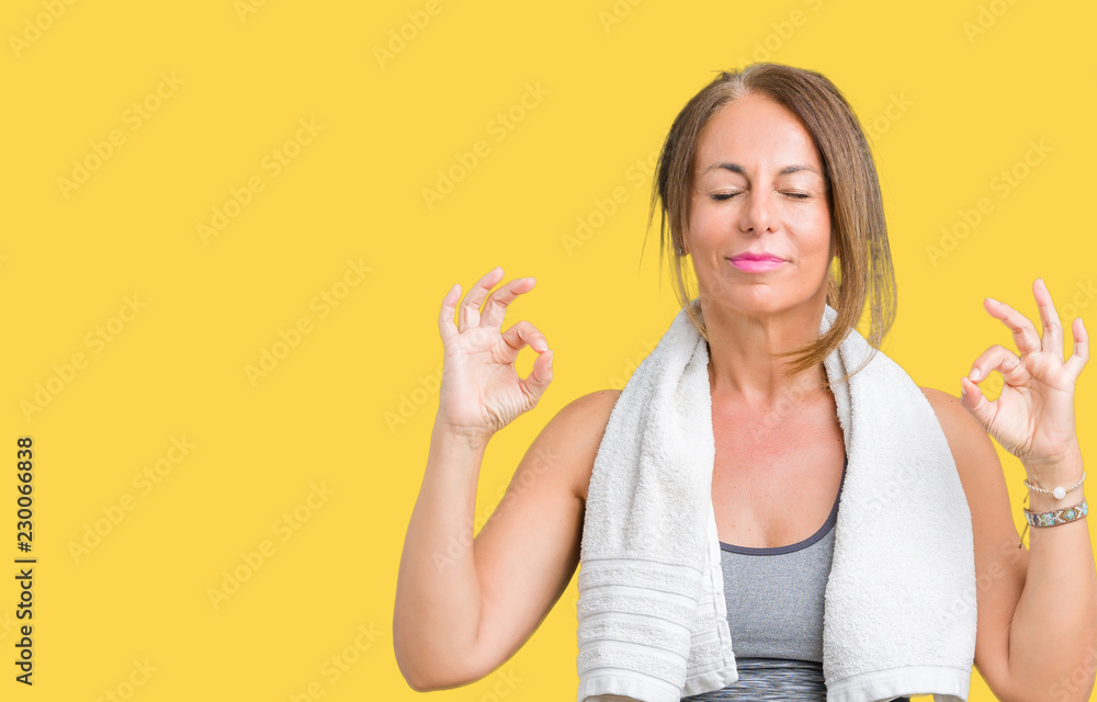Beautiful middle age woman wearing sport clothes and a towel over isolated background relax and smiling with eyes closed doing meditation gesture with fingers. Yoga concept.