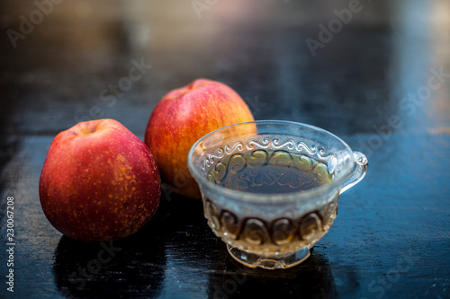 Close up of herbal apple and cinnamon tra on wooden surface in a transparent cup with raw apple. photo