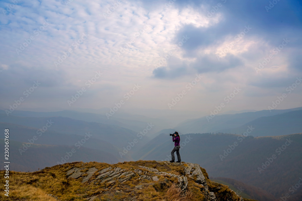 Photographer taking pictures of the mountains on a cloudy day. Beautiful autumn landscape in the mountains. Carpathian, Ukraine.