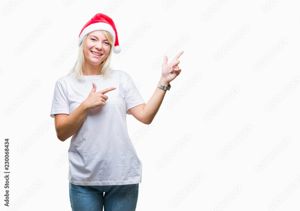 Young beautiful blonde woman wearing christmas hat over isolated background smiling and looking at the camera pointing with two hands and fingers to the side. Young beautiful blonde woman wearing christmas hat over isolated background smiling and looking at the camera pointing with two hands and fingers to the side.