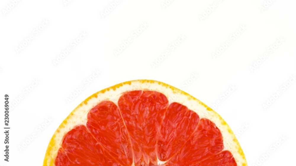 View from above. Half frame of a pink grapefruit cross section cut. Horizontally rotating on the turntable. Isolated on the white background. Close-up. Macro. View from above. Half frame of a pink grapefruit cross section cut. Horizontally rotating on the turntable. Isolated on the white background. Close-up. Macro.