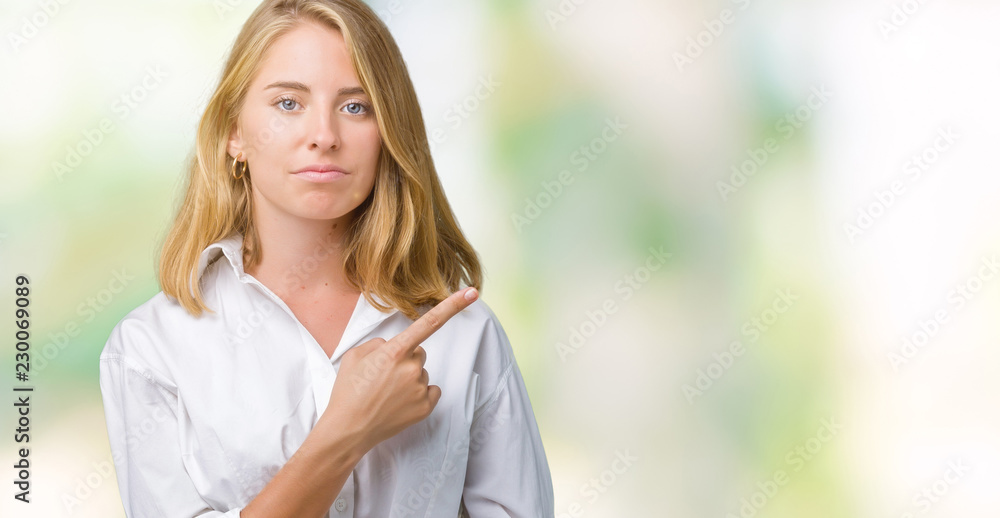 Beautiful young business woman over isolated background Pointing with hand finger to the side showing advertisement, serious and calm face Beautiful young business woman over isolated background Pointing with hand finger to the side showing advertisement, serious and calm face