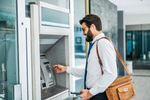Businessman using card at an ATM photo