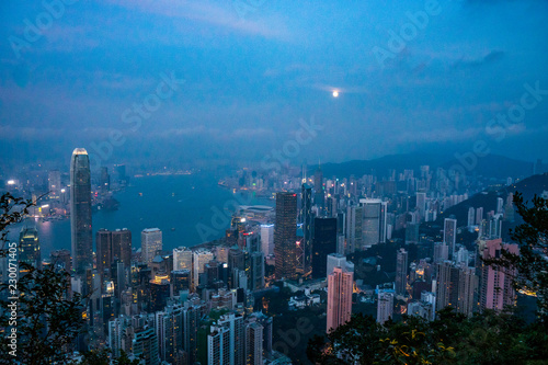 Full moon rise over Hong Kong Skyline at dusk. Modern China city with skyscrapers near the ocean