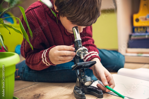 Tela Closeup portrait of little boy using microscope on biology lesson