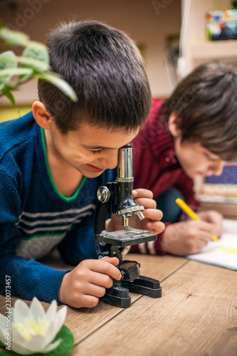 Closeup portrait of little boy using microscope on biology lesson