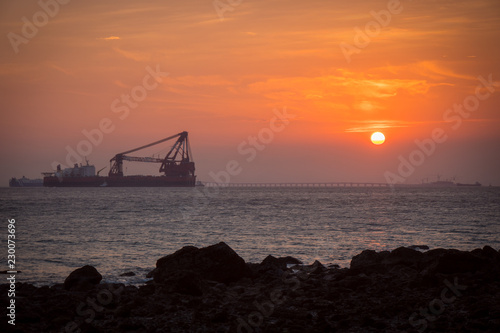 SUnset over the ocean with a crane and bridge, Hong Kong, Lantau Island