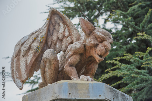 Image of a stone gargoyle sitting on top of a column with wings raised in San Martin de la Vega  Spain