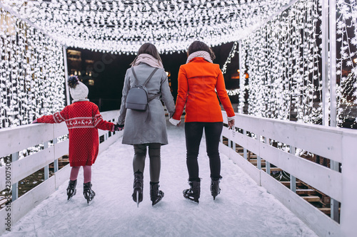 Mother with her daughter and friend enjoying in ice skating.